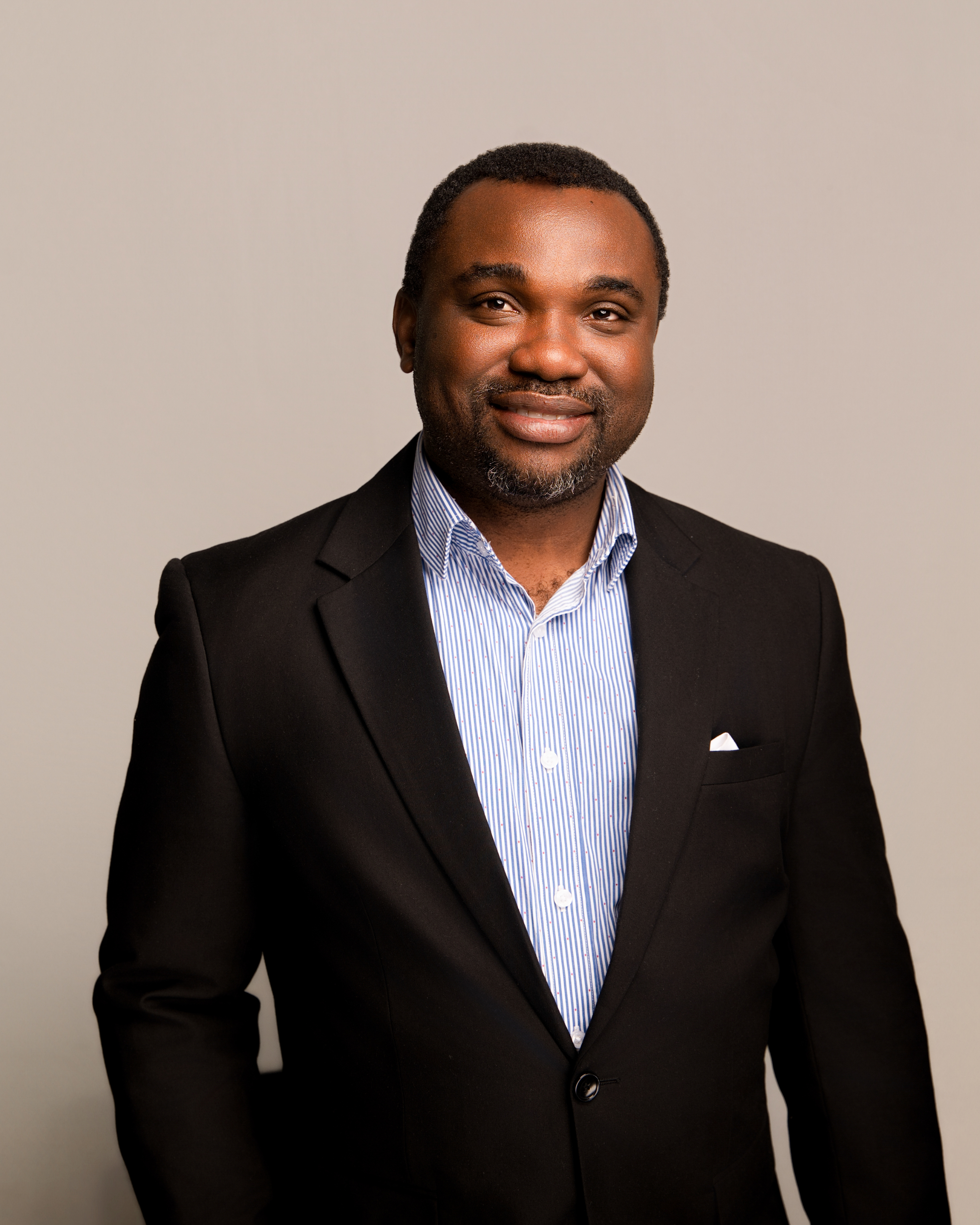 Professional headshot of smiling man in gray plaid suit